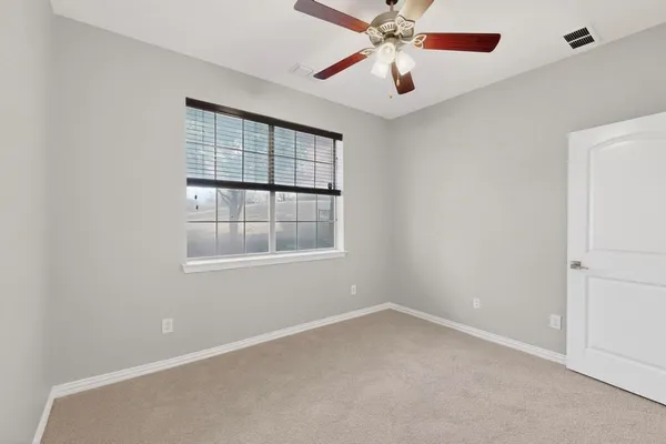 an empty room with windows and fan