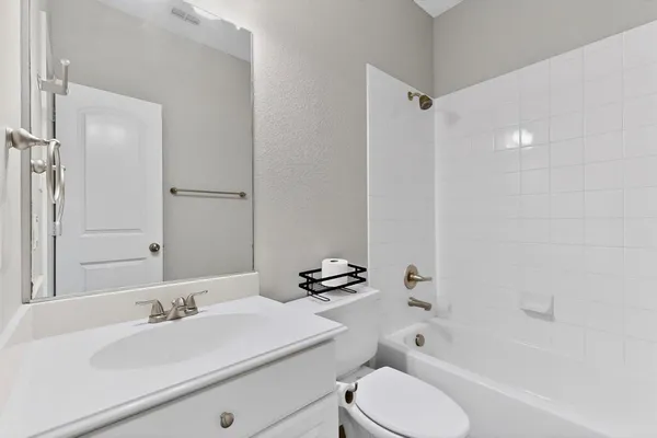 a bathroom with a bathtub shower sink vanity mirror and toilet
