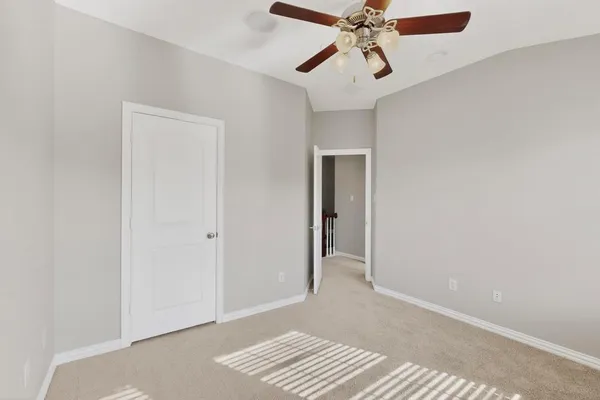 a view of an empty room with window and a ceiling fan