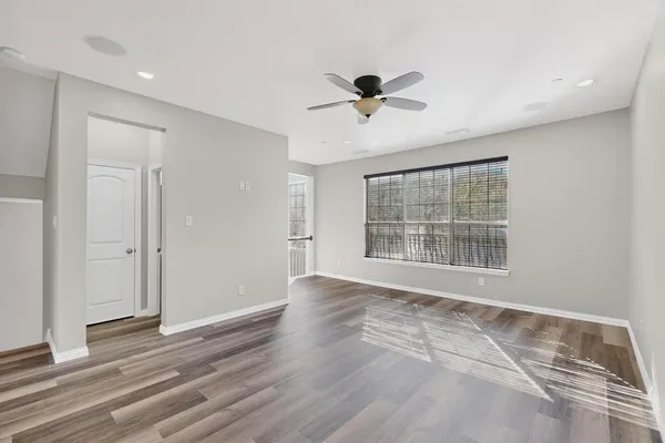 a view of an empty room with a window and wooden floor