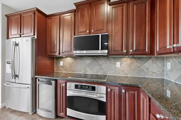 a kitchen with granite countertop wood cabinets stainless steel appliances and a sink