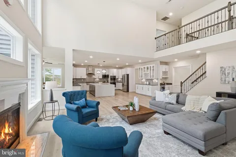 a living room with furniture kitchen view and a wooden floor
