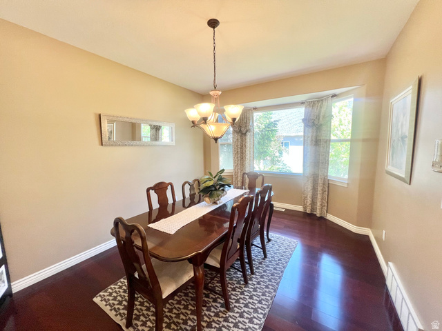 369 Culross Circle Tooele, UT 84074 - Photo 7 of 54 Formal dining space featuring dark wood-finish flooring, a bay window with natural light, and a prominent chandelier