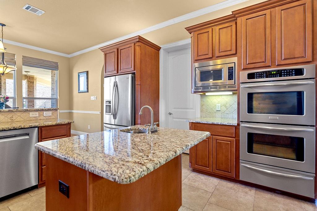117 Citation Drive Cresson, TX 76035 - Photo 16 of 40 Kitchen featuring tasteful backsplash, stainless steel appliances, ornamental molding, and light stone countertops
