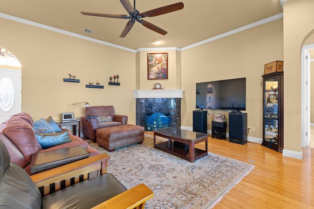 117 Citation Drive Cresson, TX 76035 - Photo 8 of 40 Living area with arched walkways, light wood-type flooring, ornamental molding, a ceiling fan, and a fireplace