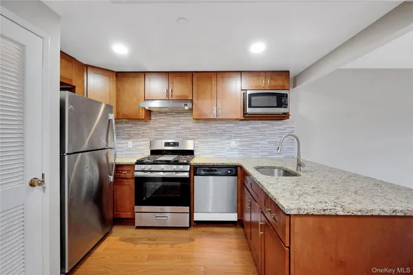 a kitchen with stainless steel appliances granite countertop a refrigerator a stove a sink and a microwave