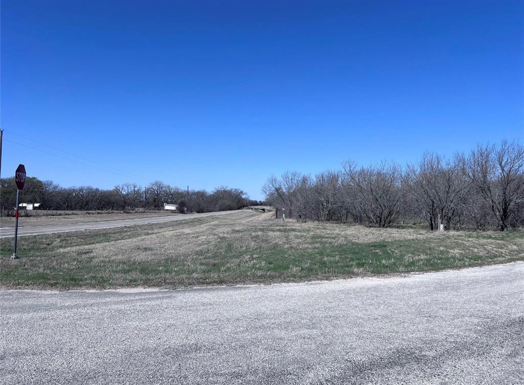 a view of dirt field with trees in background