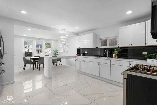 a kitchen with stainless steel appliances kitchen island granite countertop a stove a sink a dining table and chairs