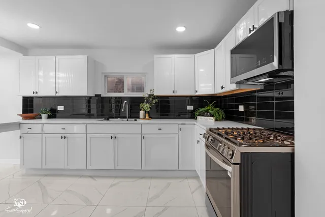 a kitchen with white cabinets and black appliances