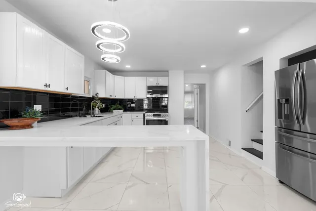 a kitchen with stainless steel appliances granite countertop a refrigerator oven a sink a stove and white cabinets