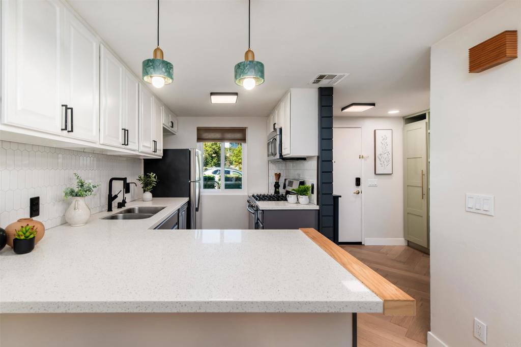 2349 Altisma Way, Unit B Carlsbad, CA 92009 - Photo 11 of 36 a large kitchen with cabinets a sink a window and stainless steel appliances
