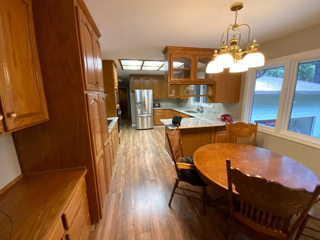 a dining room with wooden floor a chandelier a wooden table and chairs