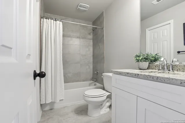 a bathroom with a granite countertop sink a toilet and shower