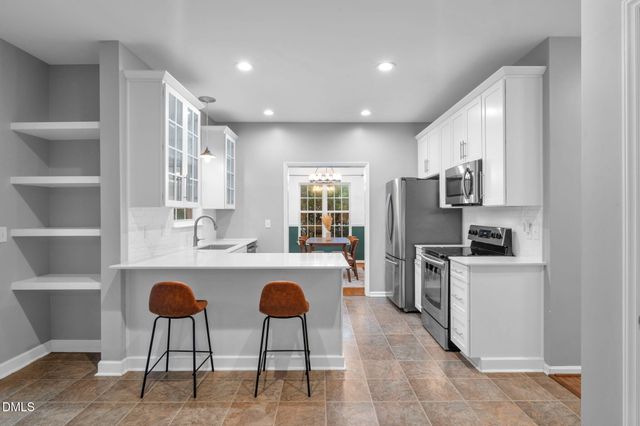 a kitchen with refrigerator and chairs