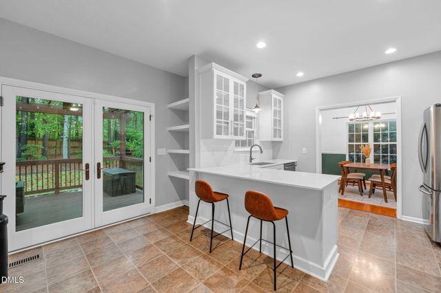 a dining hall with stainless steel appliances granite countertop a stove a sink a dining table and chairs