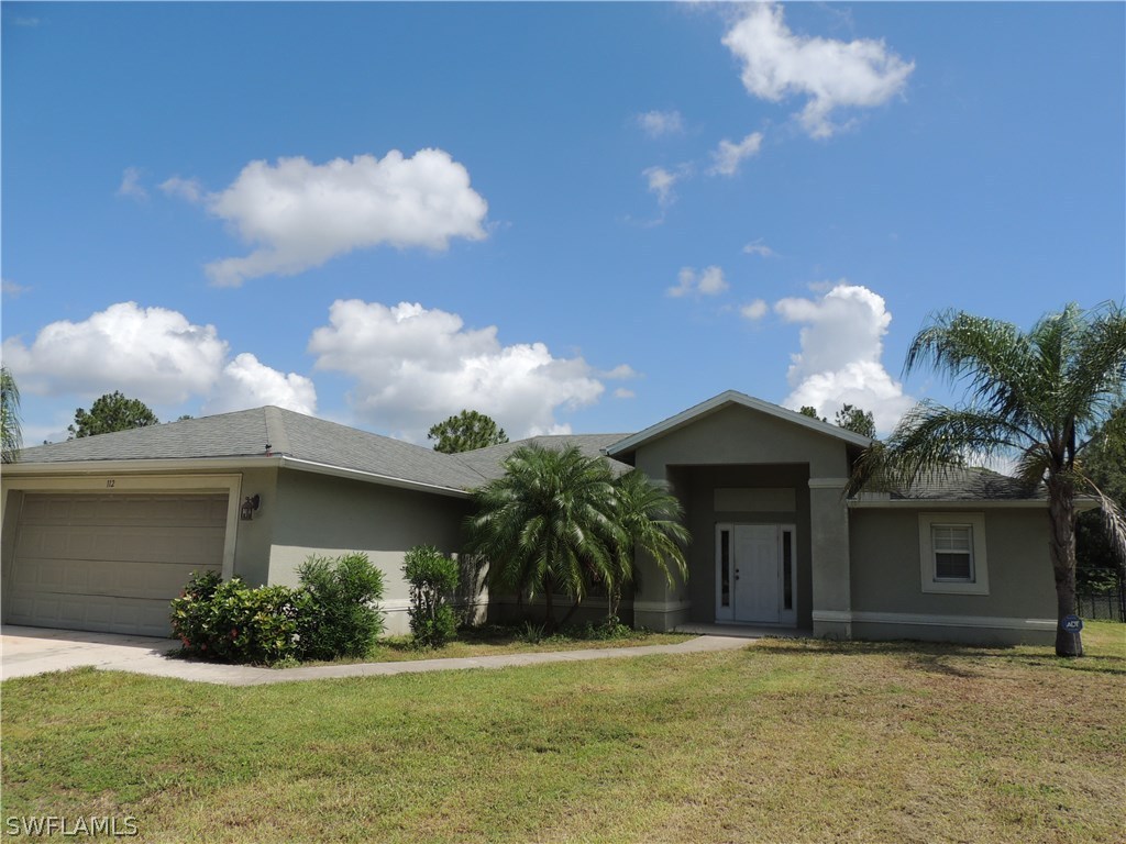 112 Ridgemont Drive Lehigh Acres, FL 33972 - Photo 1 of 18 a front view of a house with yard and green space