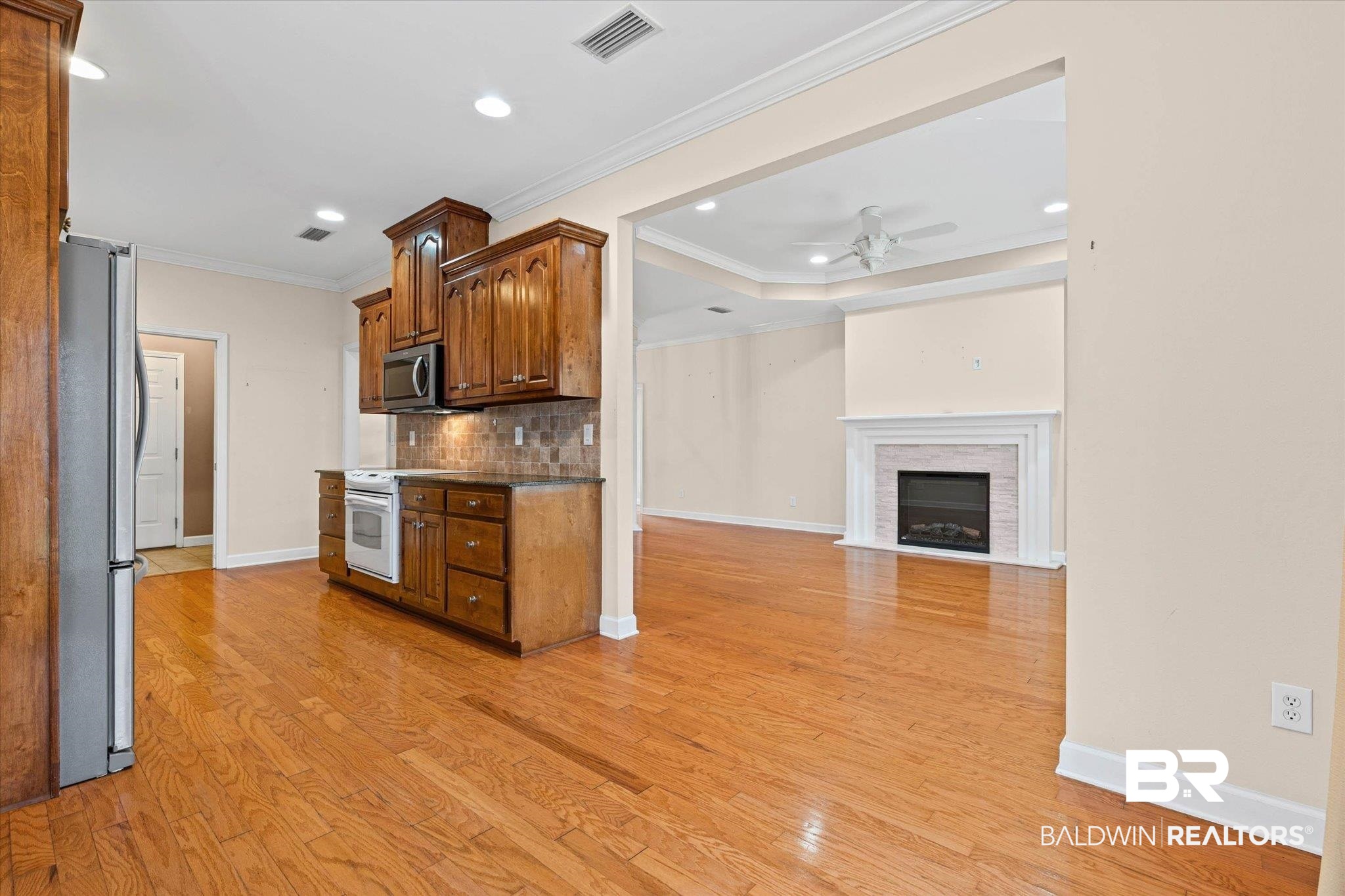 1003 Weatherby Street South Saraland, AL 36571 - Photo 18 of 31 Kitchen with wood finish cabinetry, stainless steel appliances, tasteful backsplash, dark stone counters, and a fireplace with flush hearth