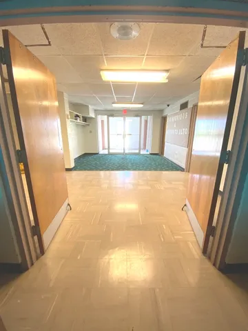 a view of an empty room with a window and a kitchen