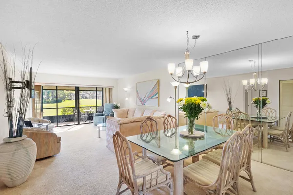 a view of a dining room with furniture a chandelier and large windows