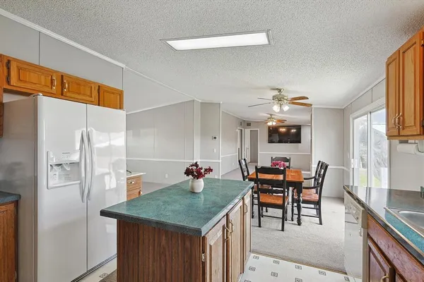 a kitchen with stainless steel appliances kitchen island granite countertop a table chairs and a refrigerator