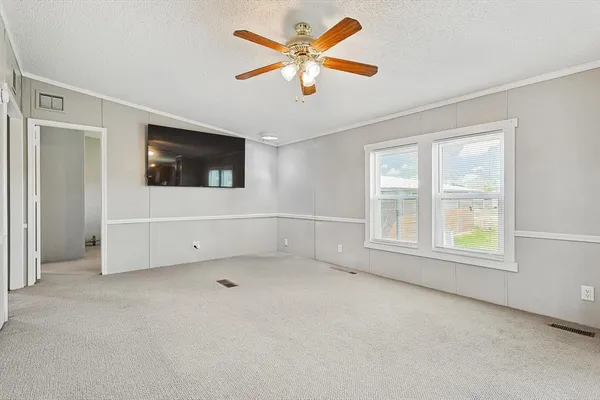 an empty room with chandelier fan and windows