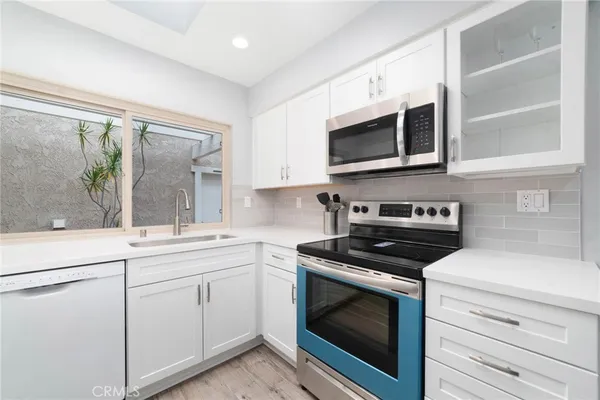 a kitchen with stainless steel appliances white cabinets and stove top oven