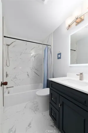 a bathroom with a granite countertop sink a toilet a mirror and shower