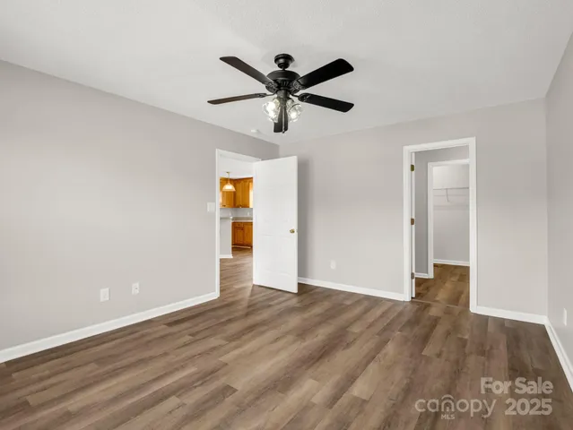 a view of empty room with wooden floor and ceiling fan