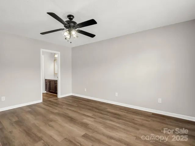 an empty room with wooden floor and ceiling fan