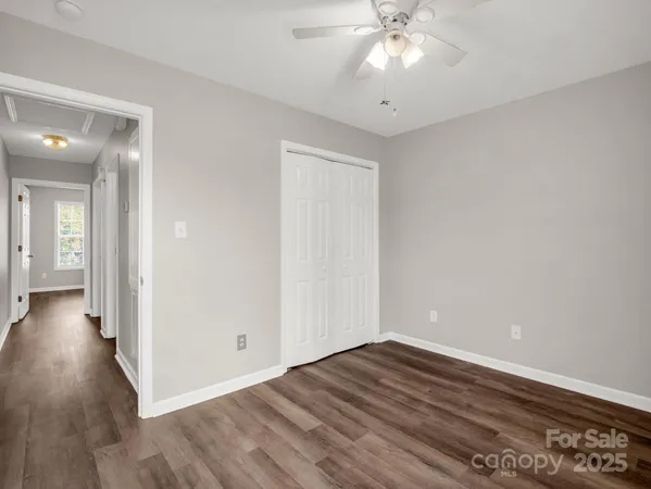 a view of a room with wooden floor and a ceiling fan