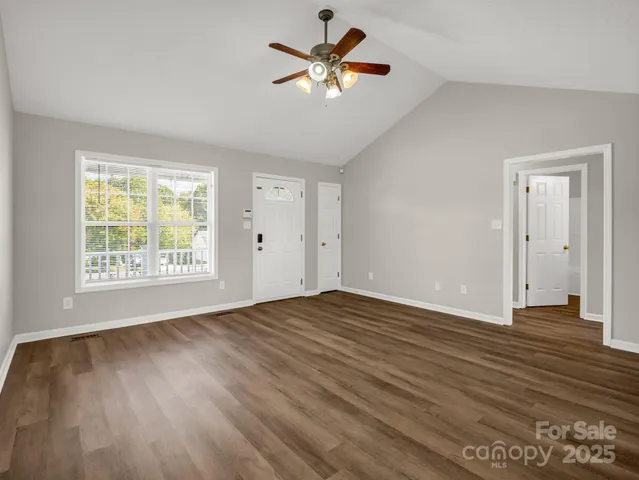a view of an empty room with window and a chandelier fan