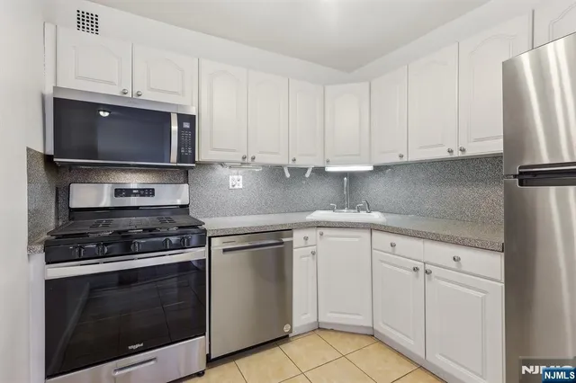 a kitchen with white cabinets and appliances