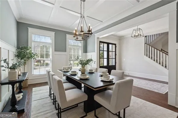 a dining room with wooden floor a chandelier a wooden table and chairs