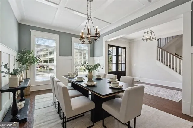a dining room with wooden floor a chandelier a wooden table and chairs
