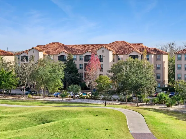 a view of a building with a swimming pool and a lawn chairs under an umbrella