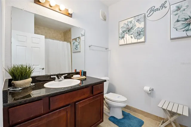 a bathroom with a granite countertop sink mirror and toilet