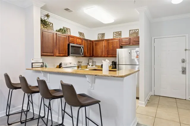 a kitchen with stainless steel appliances granite countertop a stove top oven a sink dishwasher and a refrigerator with wooden cabinets