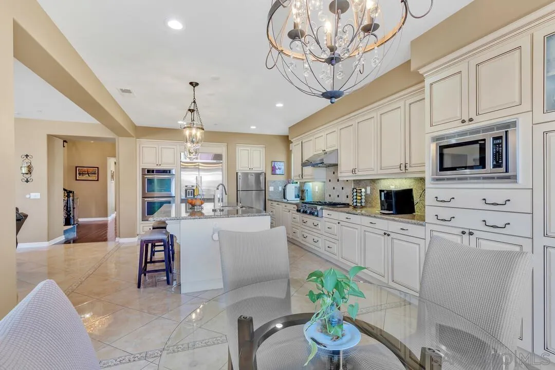 14622 Whispering Ridge Road San Diego, CA 92131 - Photo 20 of 75 a kitchen with stainless steel appliances granite countertop a refrigerator a stove a sink dishwasher and white cabinets with wooden floor