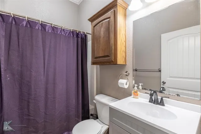 a bathroom with a sink a toilet a mirror and shower curtain