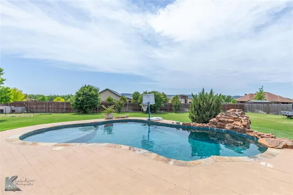 an outdoor view of a patio with swimming pool and furniture