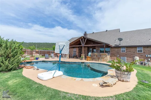 an outdoor view of house with swimming pool and furniture