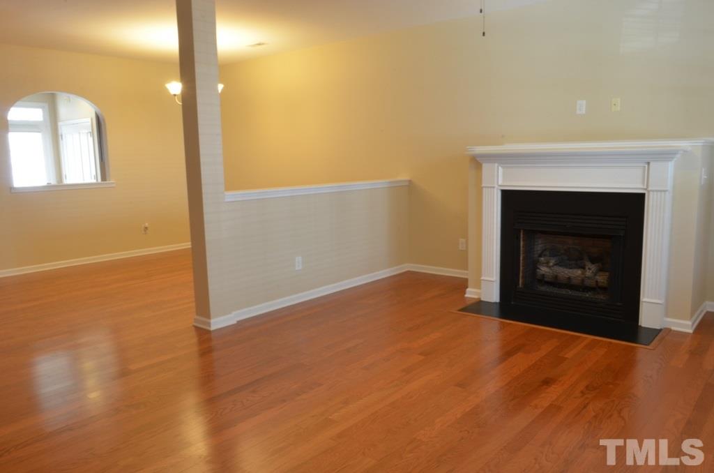 509 Dragby Lane Raleigh, NC 27603 - Photo 4 of 25 an empty room with a fireplace and wooden floor
