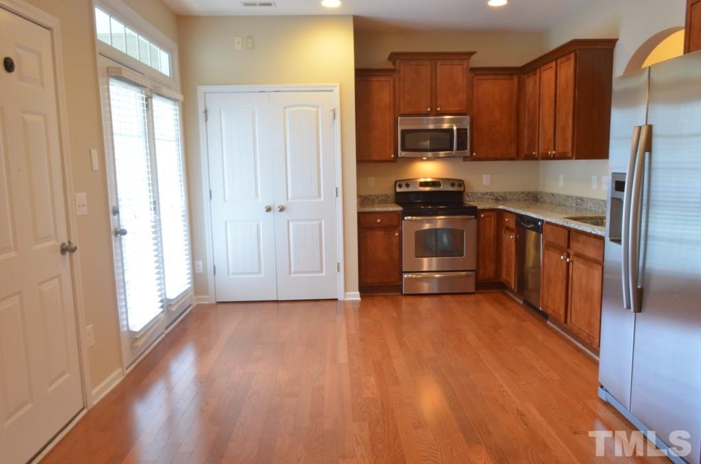 509 Dragby Lane Raleigh, NC 27603 - Photo 9 of 25 a kitchen with granite countertop wooden floors stainless steel appliances and a window