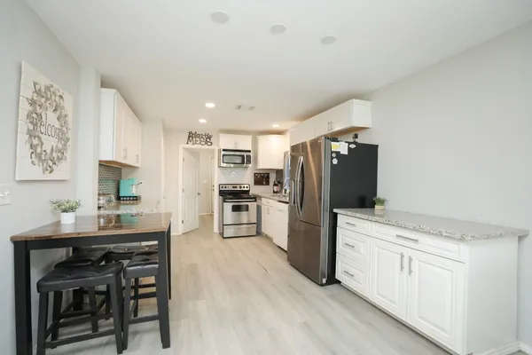 a kitchen with stainless steel appliances granite countertop a refrigerator a stove a sink and a microwave