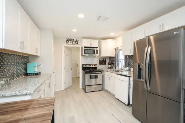 a kitchen with stainless steel appliances granite countertop white cabinets a stove a sink and dishwasher