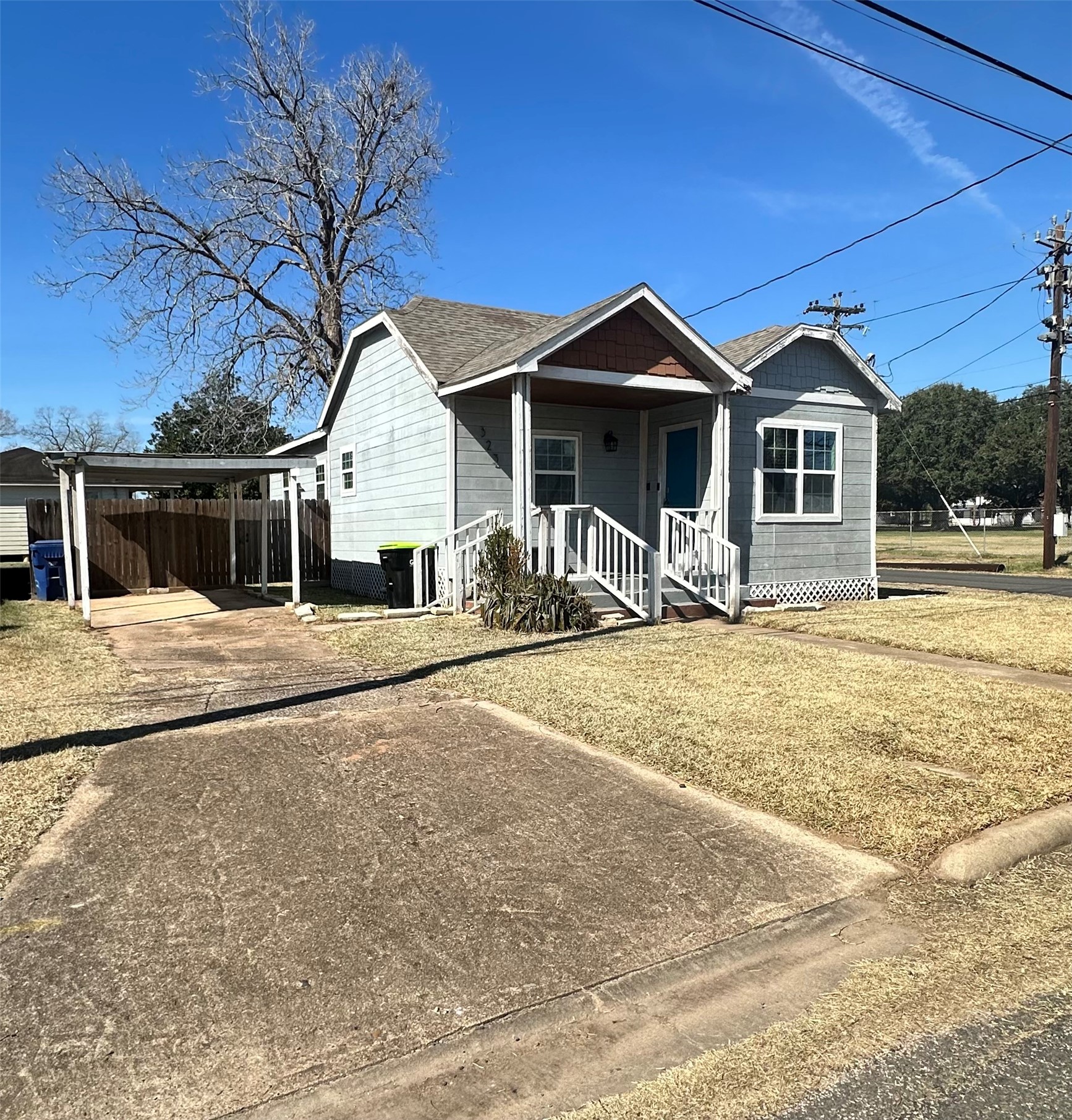 323 North Outlar Street Wharton, TX 77488 - Photo 2 of 25 a view of a house with large trees and wooden fence