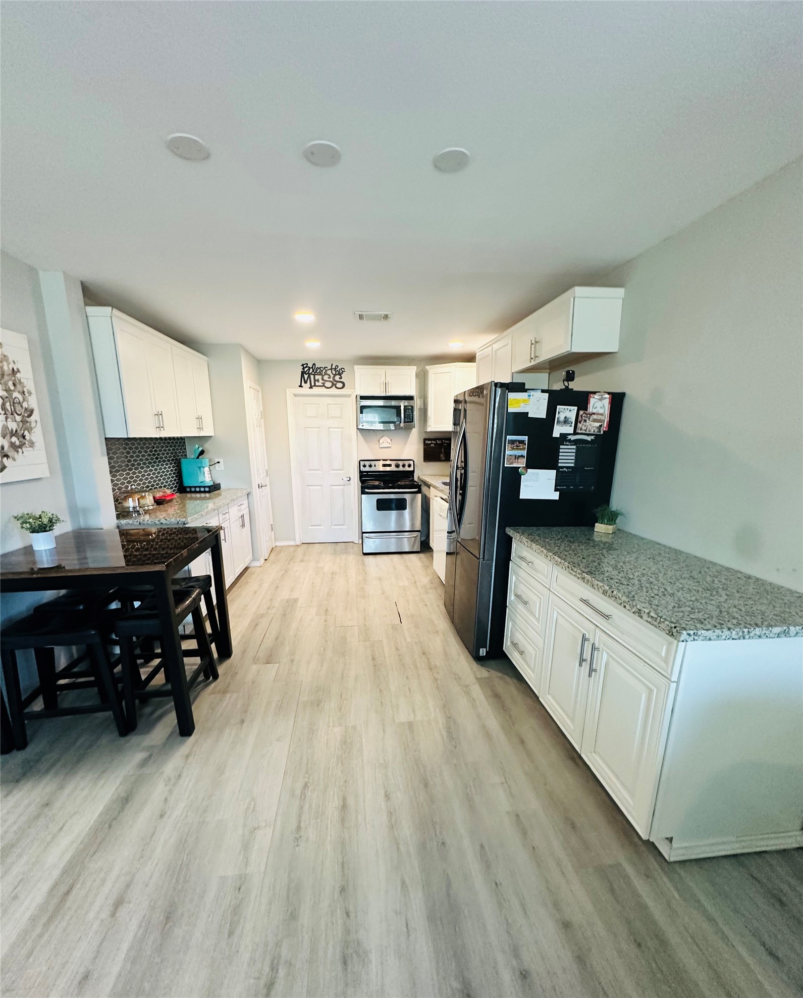 323 North Outlar Street Wharton, TX 77488 - Photo 4 of 25 a kitchen with stainless steel appliances wooden floor and a refrigerator