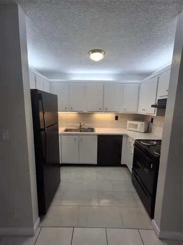 a kitchen with a sink a refrigerator and black cabinets