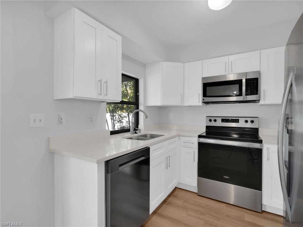 4991 18th Court Southwest Naples, FL 34116 - Photo 14 of 36 a kitchen with stainless steel appliances granite countertop a stove a microwave and a sink