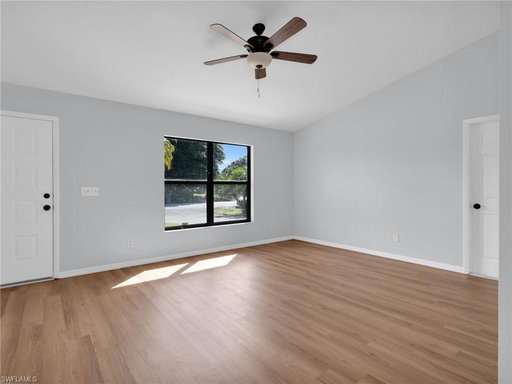 4991 18th Court Southwest Naples, FL 34116 - Photo 9 of 36 an empty room with wooden floor chandelier fan and windows
